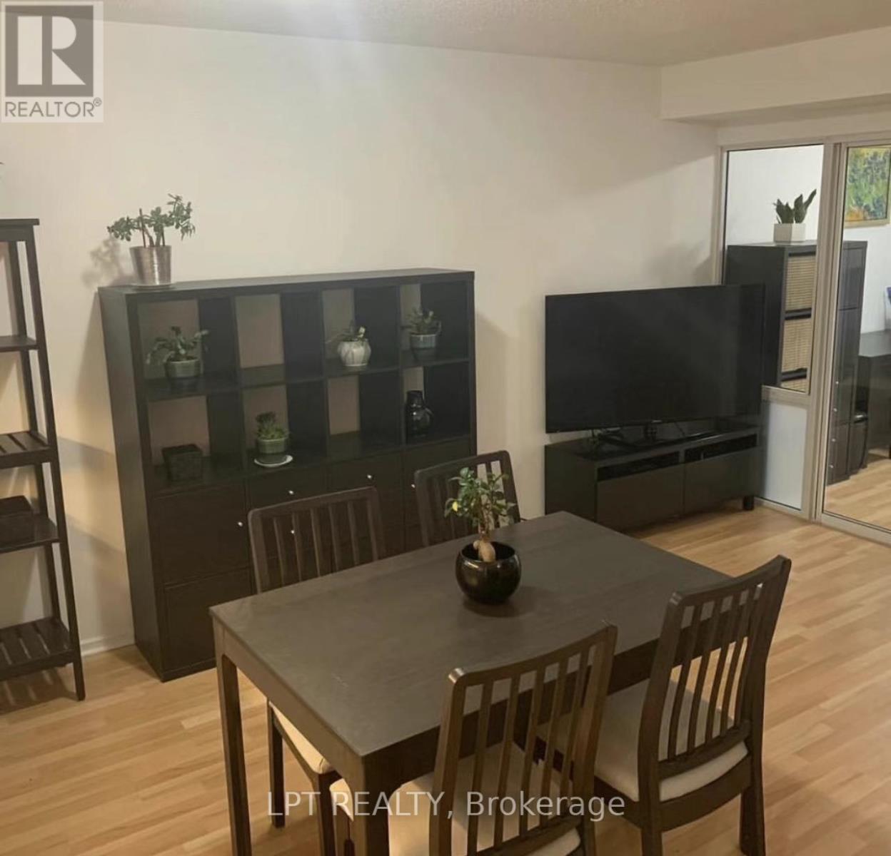A dining room with a table set for two and a television in the corner.