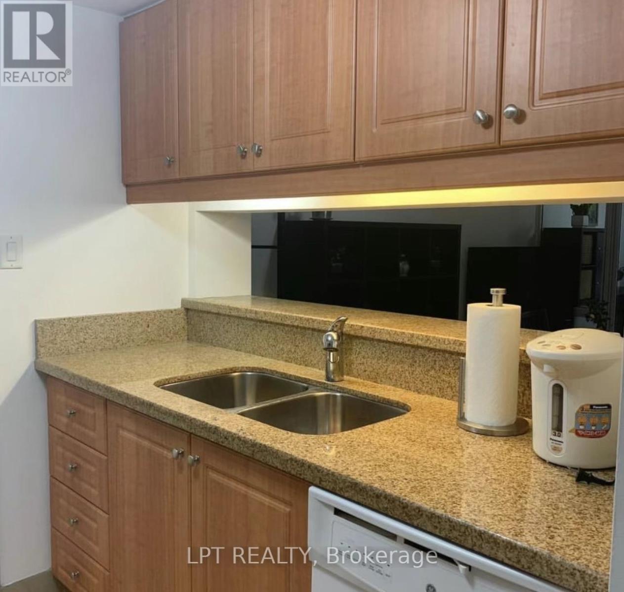 A kitchen with a sink and a coffee maker on the counter.