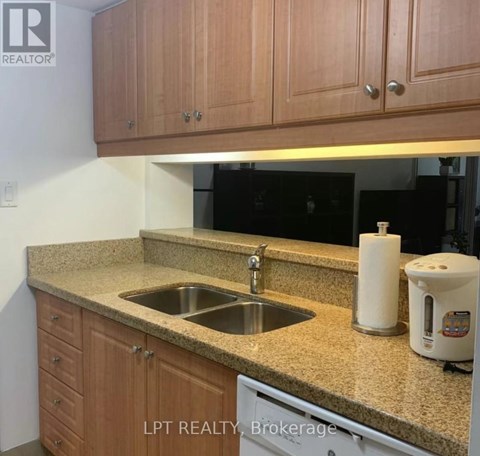A kitchen with a sink and a coffee maker on the counter.