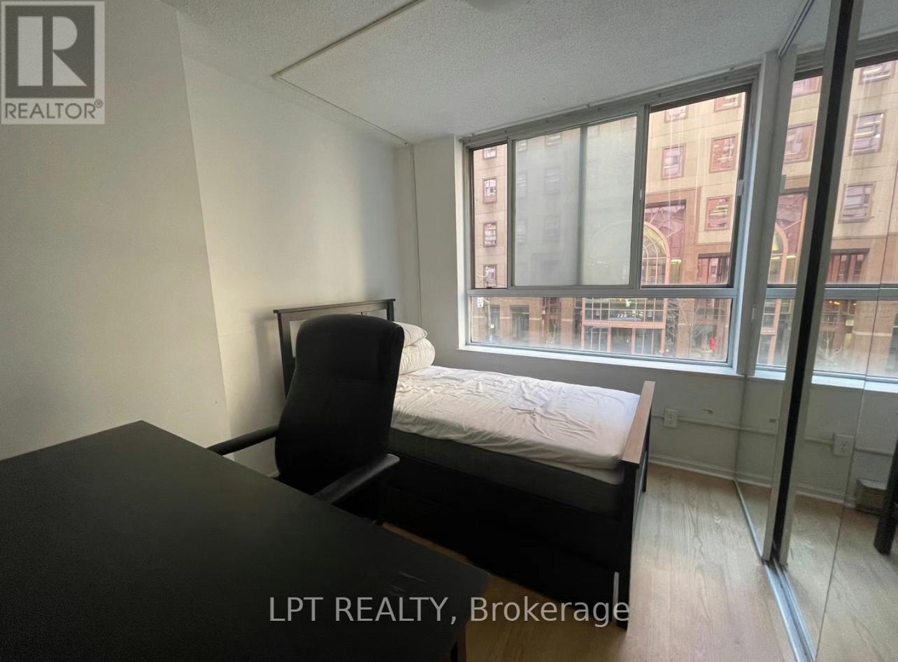 A bedroom with a bed, chair, and a window overlooking a cityscape.