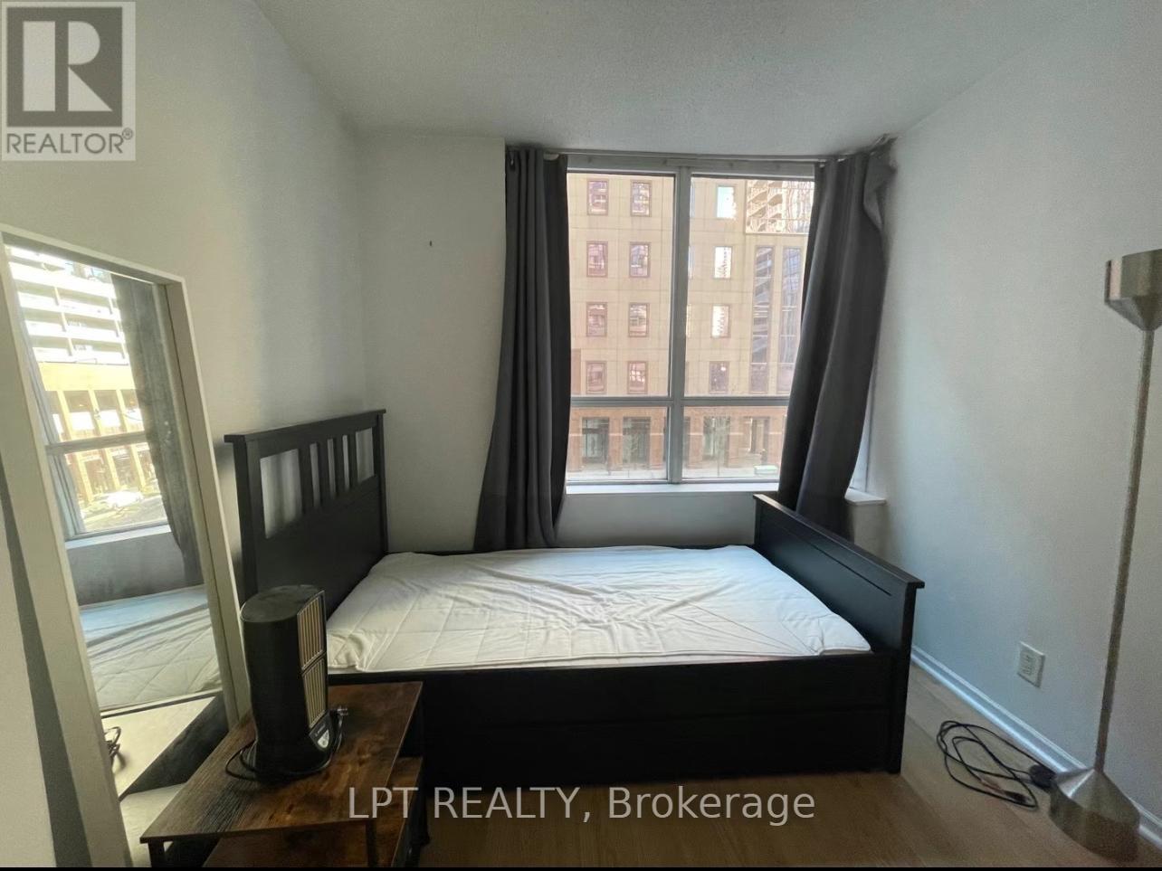 A bedroom with a large bed and a window overlooking a cityscape.