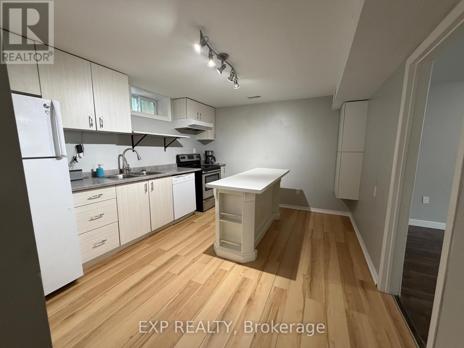 A kitchen with white cabinets and a wooden floor.