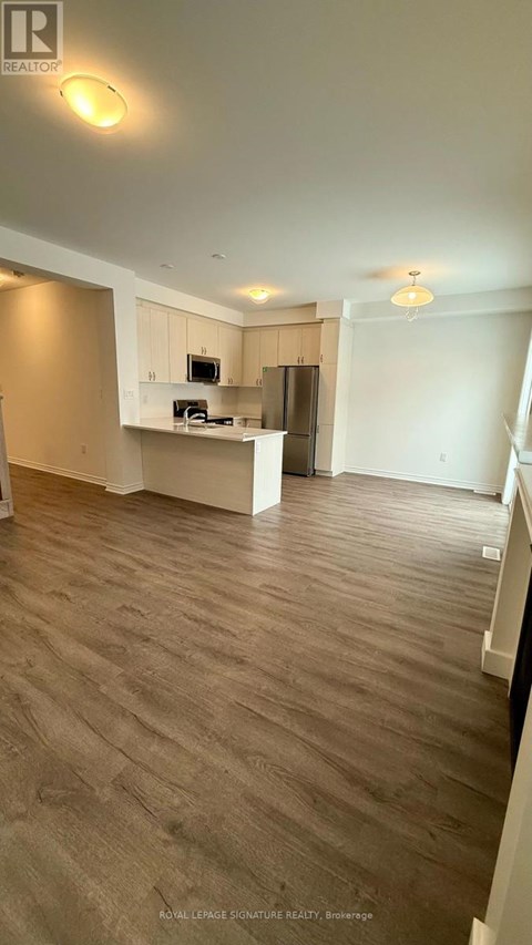 A spacious living room with a kitchenette in the background.