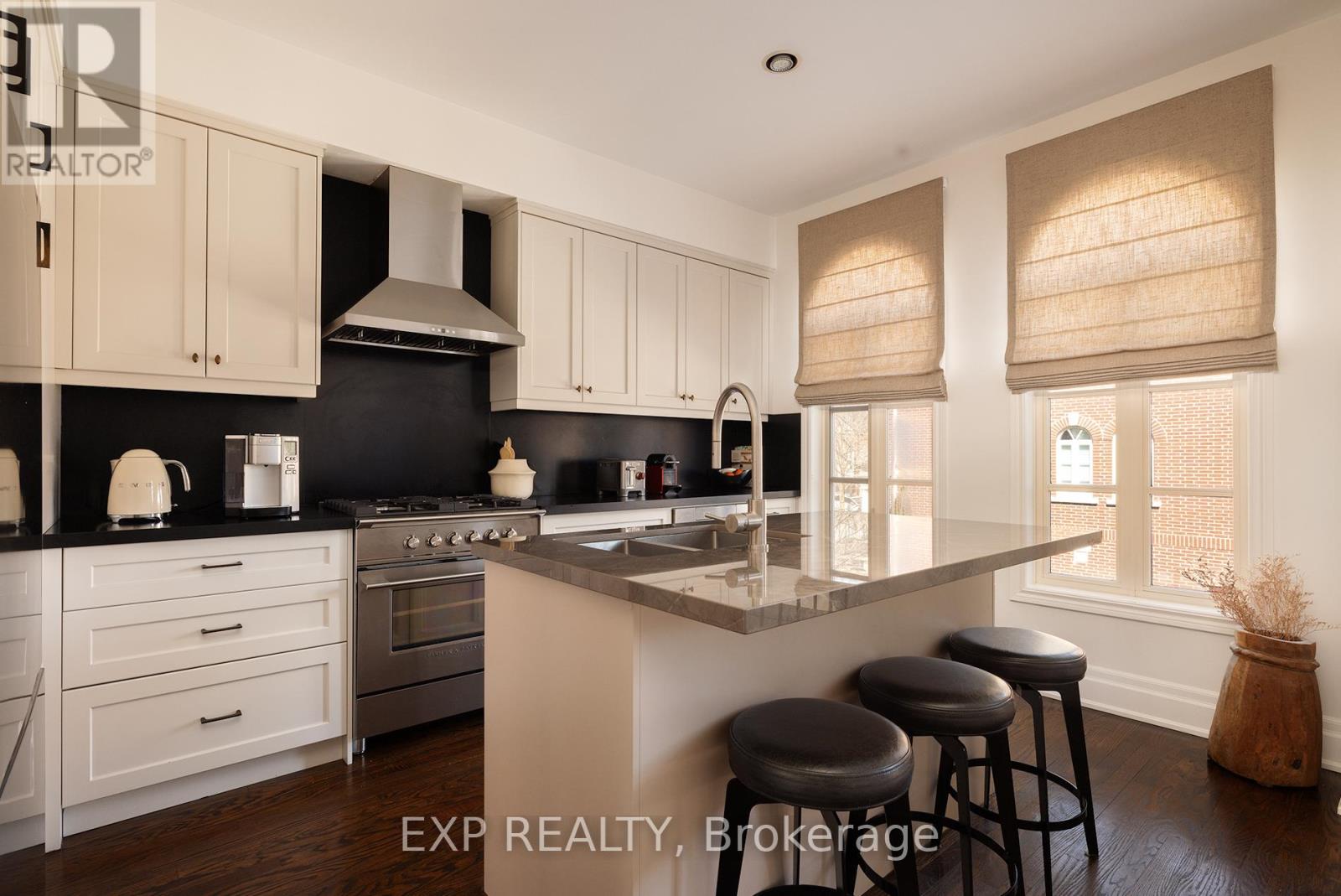 A kitchen with white cabinets and black countertops.