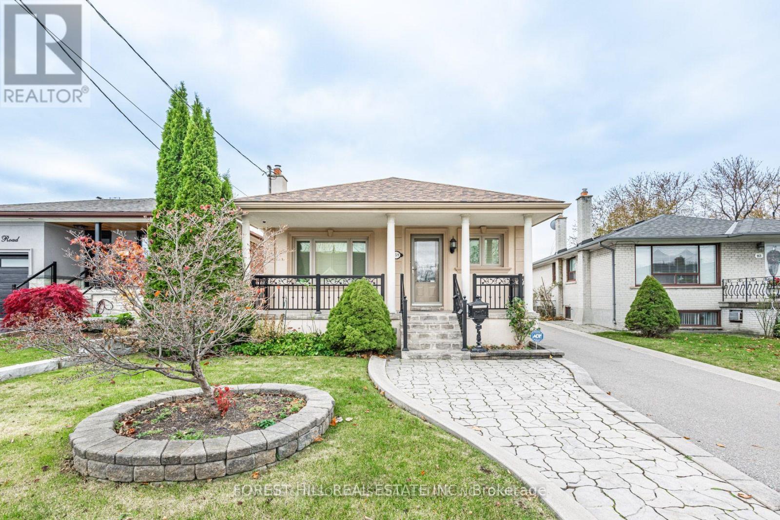 A house with a front yard and a small tree in a circular flower bed.