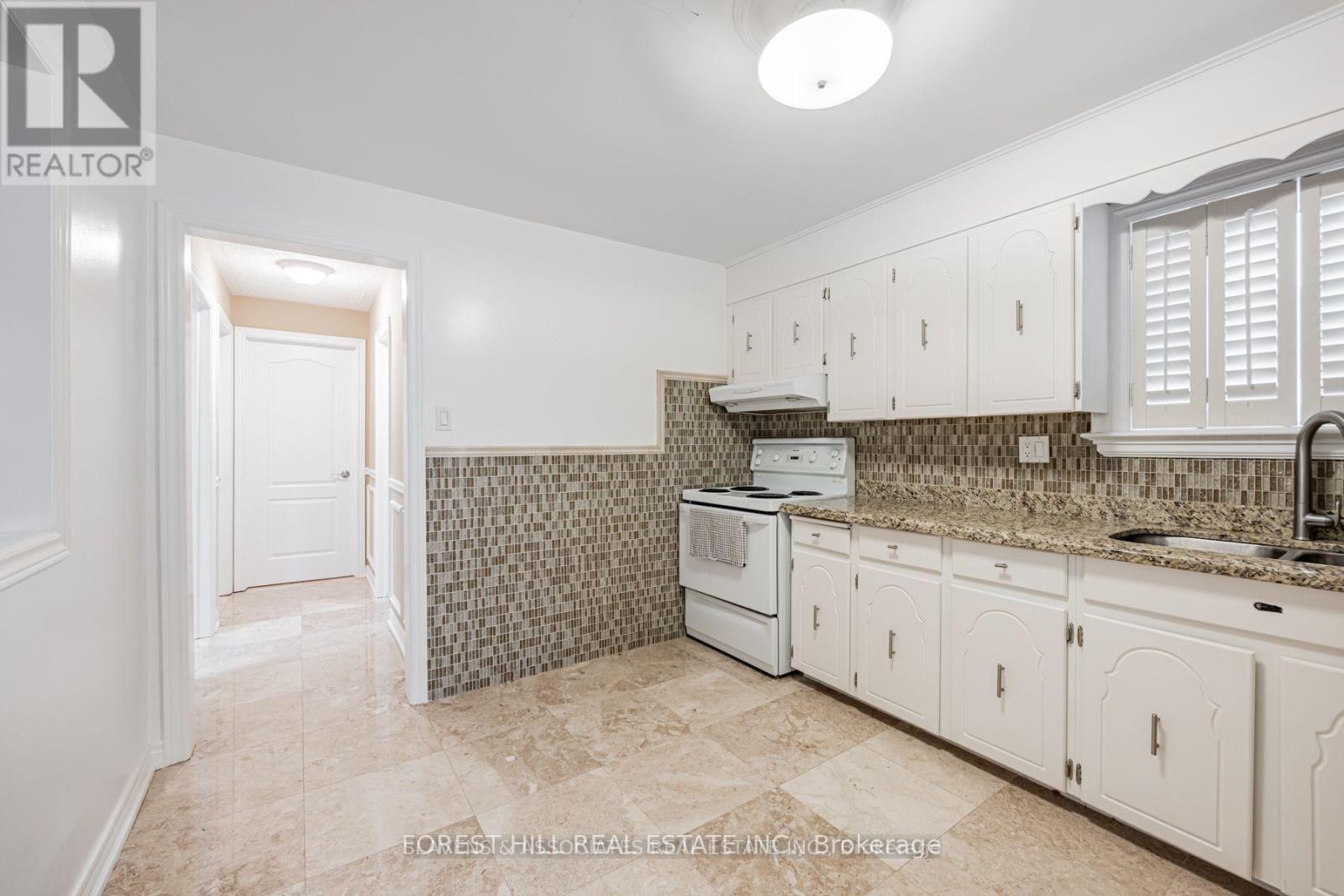 A kitchen with white cabinets and a tiled backsplash.