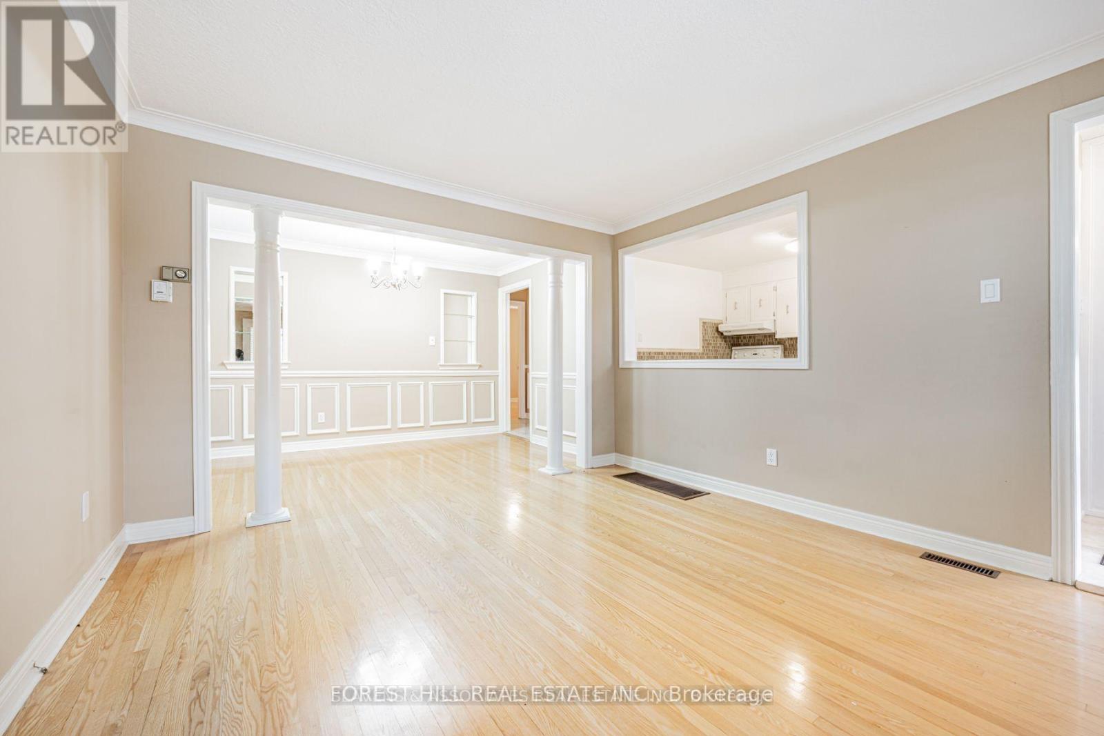 A spacious room with wooden flooring and white walls.