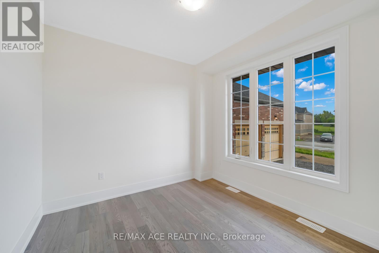A room with a large window showing a view of a house and trees outside.