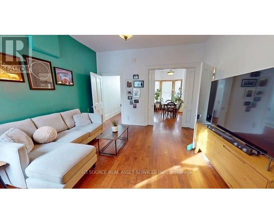 A living room with a white couch and a wooden floor.