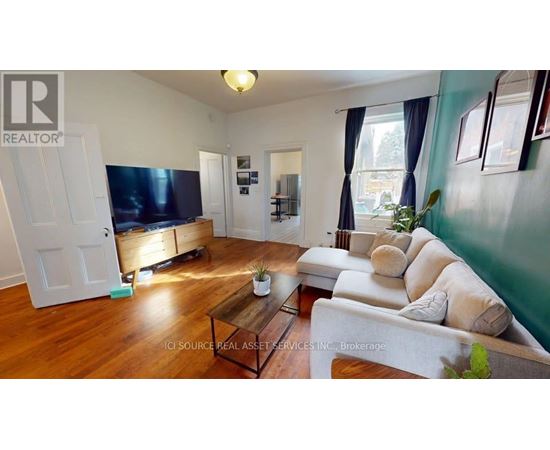 A living room with a flat screen TV and a white sofa.