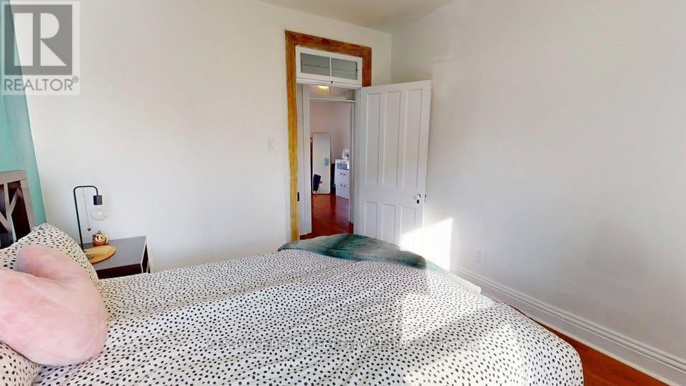 A bedroom with a bed, nightstand, and a doorway leading to another room.