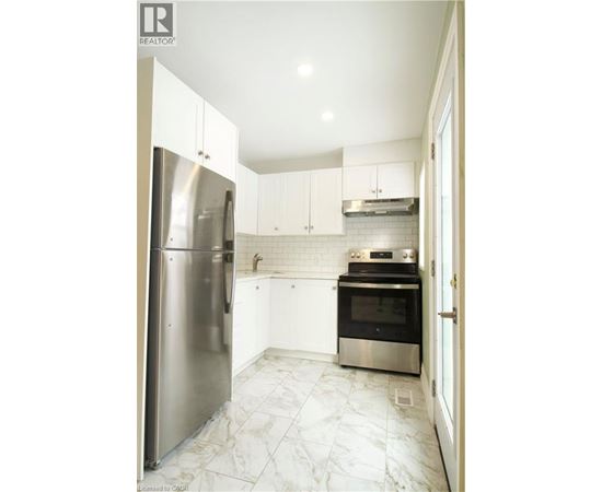 A kitchen with a refrigerator, oven, and stove.
