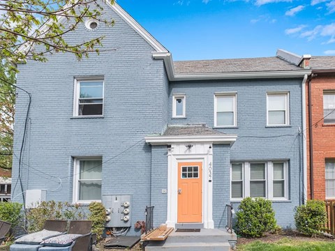 A blue house with a red door and a small porch.