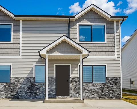 A modern house with a stone wall and a black door.