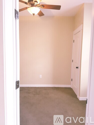 A room with a ceiling fan and a door.