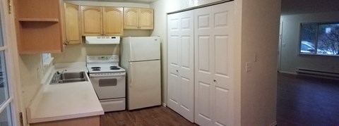 A kitchen with white appliances and wooden cabinets.