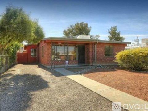 A red brick house with a gravel driveway in front.