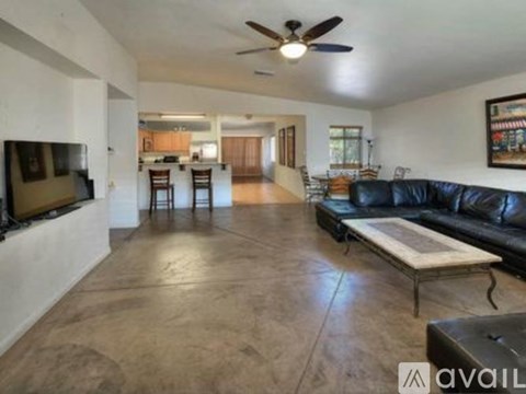 A living room with a black leather couch and a television.