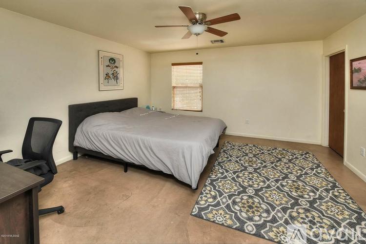 A bedroom with a bed, chair, and rug.