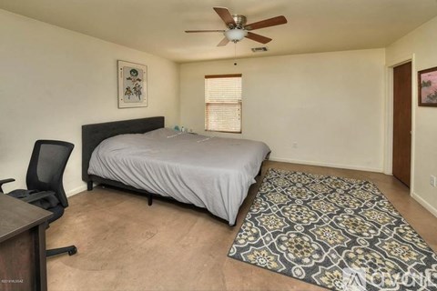 A bedroom with a bed, chair, and rug.