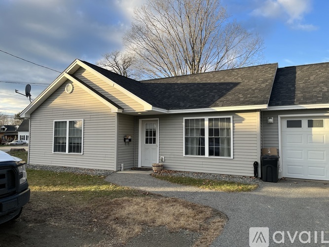 A house with a grey roof and a white garage door is for sale.