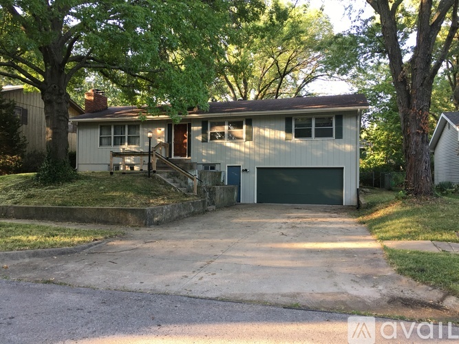 A house with a garage is surrounded by trees.