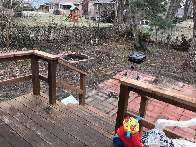A backyard with a wooden deck and a BBQ grill.