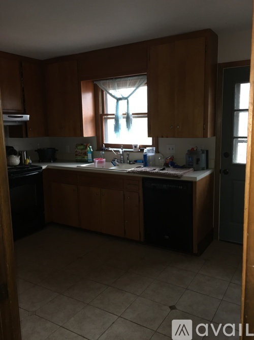 A kitchen with wooden cabinets and a black dishwasher.