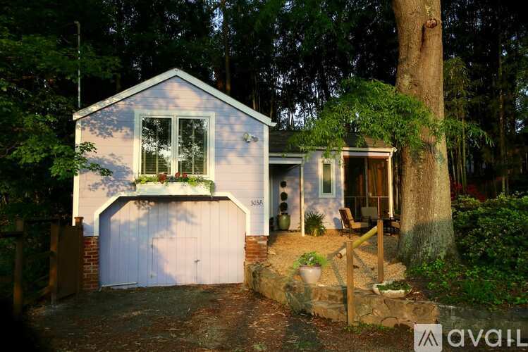 A white house with a garage is surrounded by trees.