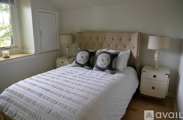 A bedroom with a large bed, a nightstand, and a window.