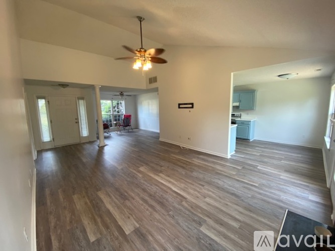 A spacious room with wooden flooring and a ceiling fan.
