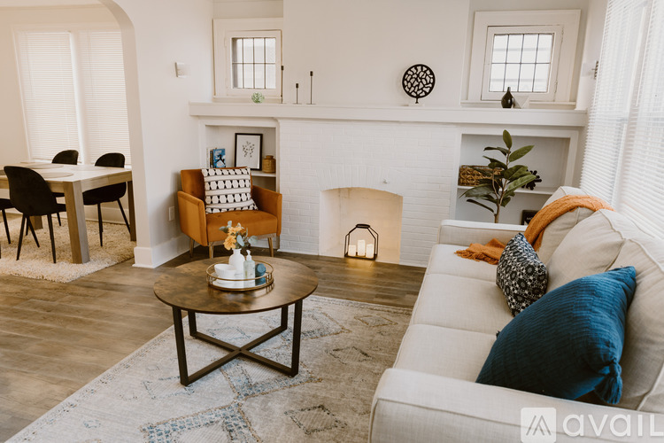 A living room with a white couch, a coffee table, and a dining table with chairs.