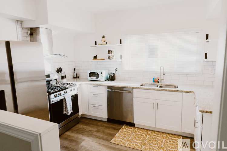 A kitchen with a white fridge, stove, and sink.