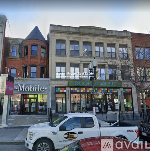 A white truck is parked in front of a book and music store.