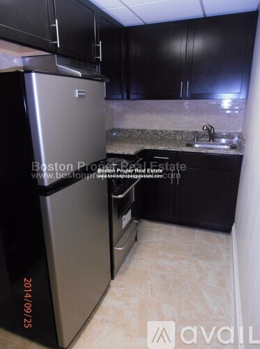 A kitchen with a stainless steel refrigerator and black cabinets.