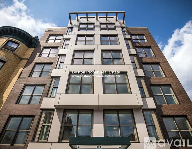 A tall building with a balcony and a sign that says Boston Proper Real Estate.