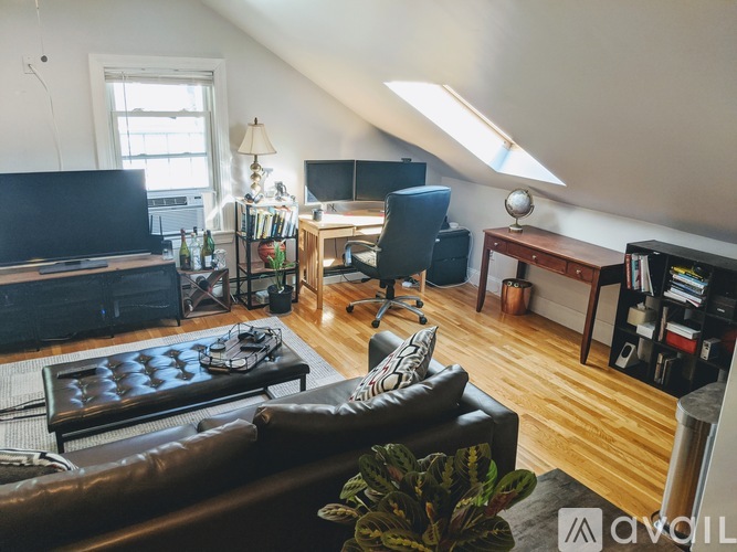 A living room with a brown leather couch and a wooden floor.