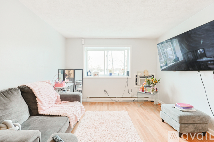 A living room with a grey couch and a pink blanket on it.