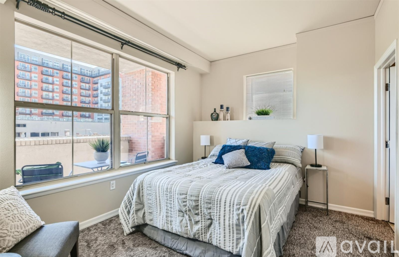 A bedroom with a large bed and a window overlooking a cityscape.