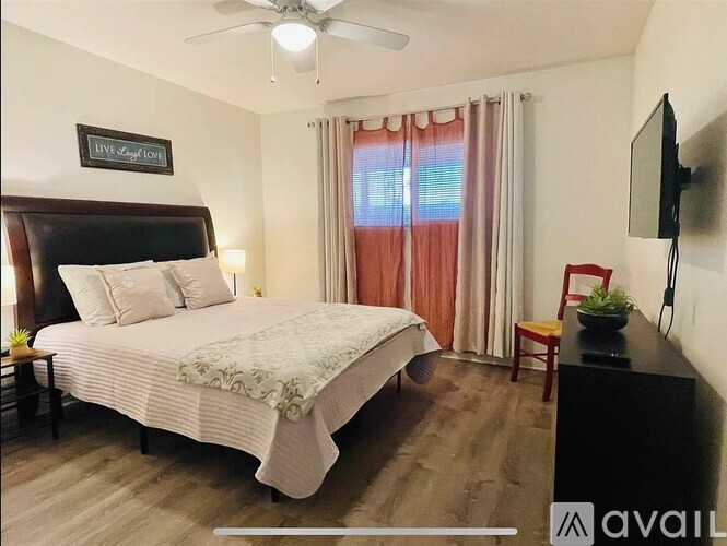A bedroom with a large bed, a flat screen TV, and a ceiling fan.