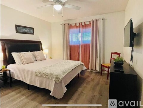 A bedroom with a large bed, a flat screen TV, and a ceiling fan.