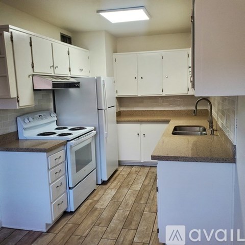 A kitchen with white cabinets and a stove top oven.
