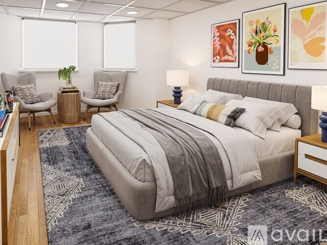 A bedroom with a large bed, two chairs, and a rug.
