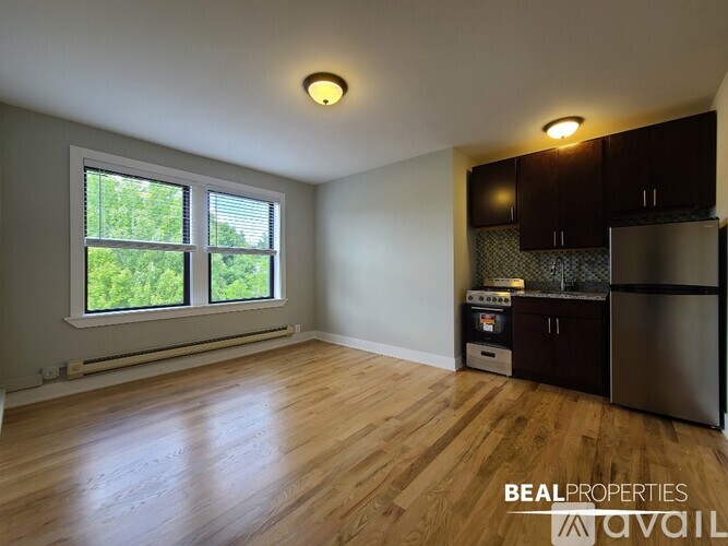 A kitchen area with wooden floors and a window with greenery outside.