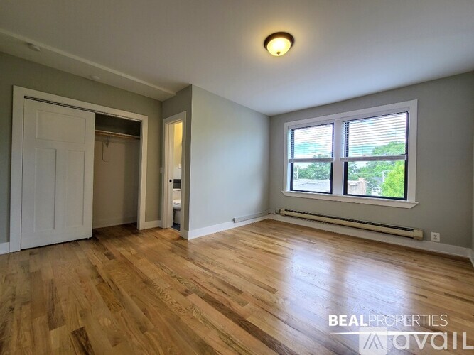 A room with wooden flooring and a window with blinds.