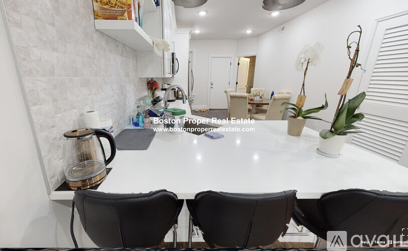 A kitchen with white countertops and black chairs.