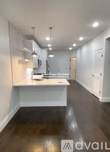 A spacious kitchen with a long counter and pendant lights.