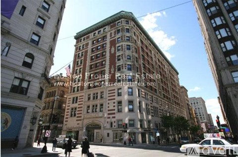 A street view of a city with a large building in the middle.