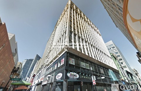 A tall building with a curved facade stands in the middle of a city street.