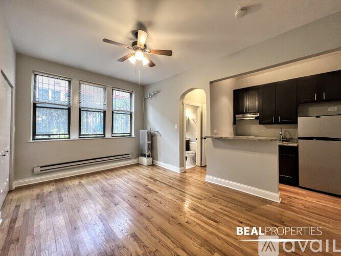 A spacious room with a ceiling fan and wooden flooring.